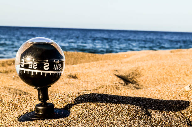 A push pin is positioned in the middle of a compass rose on a map with navigational lines intersecting with the pushpin.