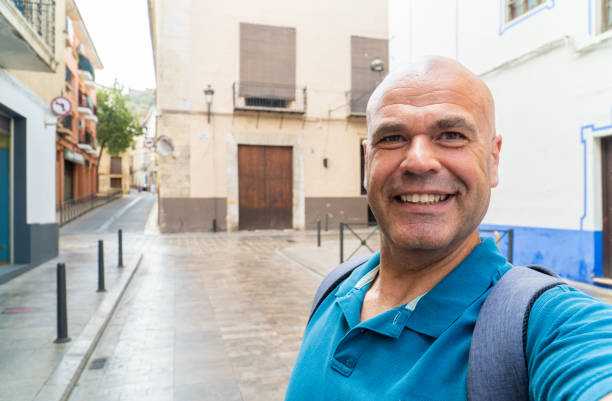 Smiling tourist looking at the camera, takes a selfie in the old city quarter.