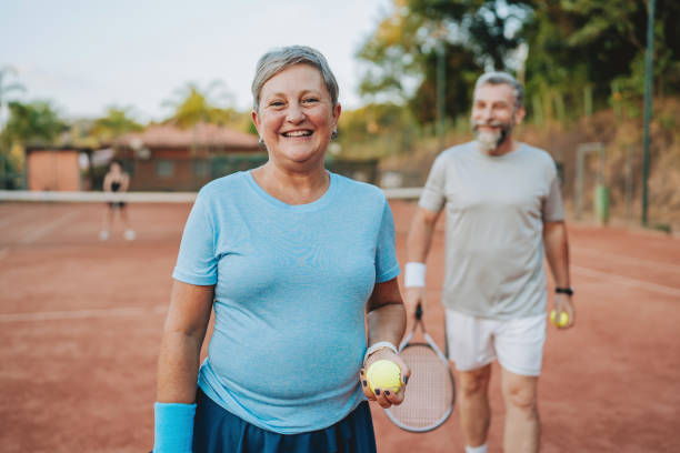 istock Senior couple playing tennis looking at camera 2154343111