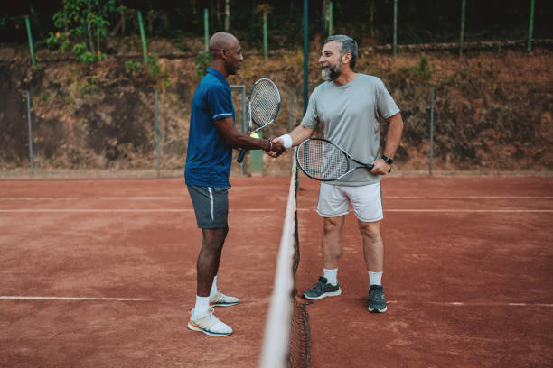 istock two friends playing tennis greet at the net 2154343293