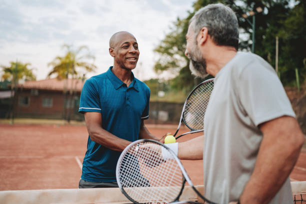 istock two friends playing tennis greet at the net 2154343305