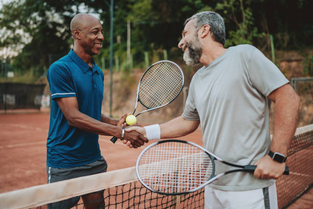 istock two friends playing tennis greet at the net 2154343307
