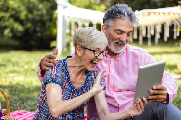 istock Senior couple sitting on blanket and using digital tablet 2154350995