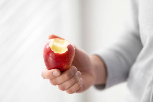 istock male hand holding bitten apple, man eating an apple close up selective focus 2154351821