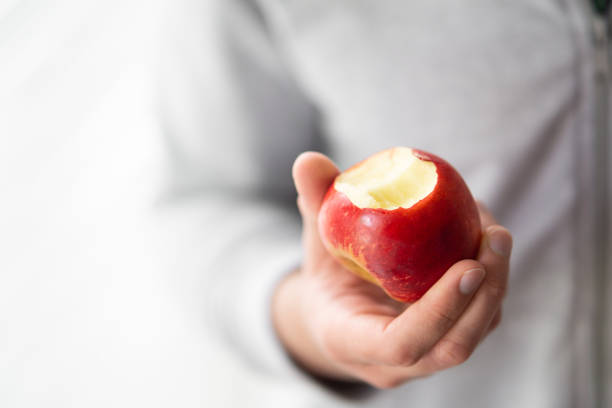 male hand holding bitten apple, man eating an apple close up selective focus