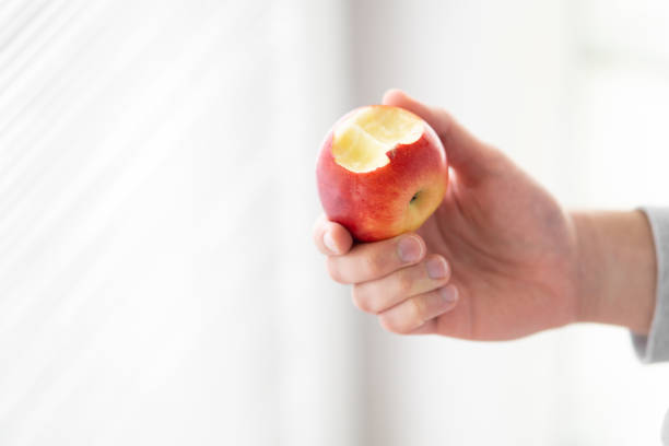 istock male hand holding bitten apple, man eating an apple close up selective focus 2154351833