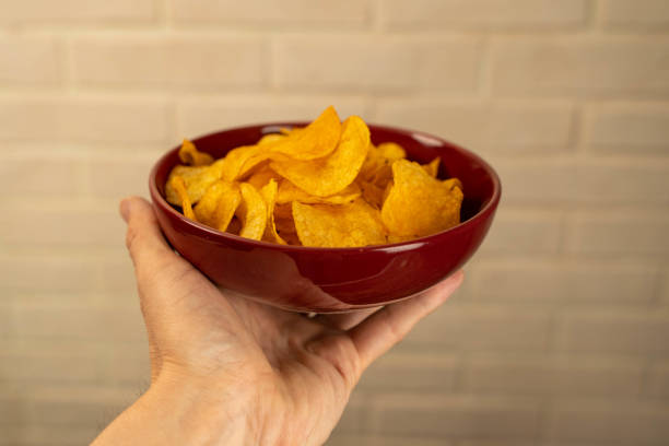 istock A hand holding a red bowl filled with potato chips 2154351900