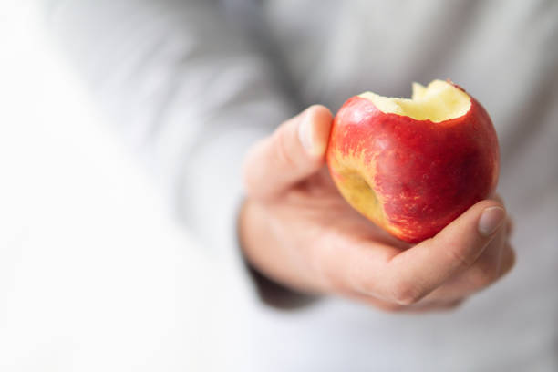 istock male hand holding bitten apple, man eating an apple close up selective focus 2154351987