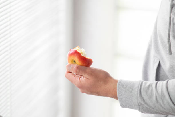 male hand holding bitten apple, man eating an apple close up selective focus