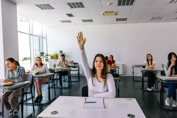 istock Female student raising her hand in class to ask some question. 2154352286
