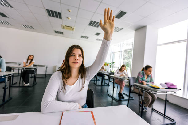 istock Female student raising her hand in class to ask some question. 2154352290