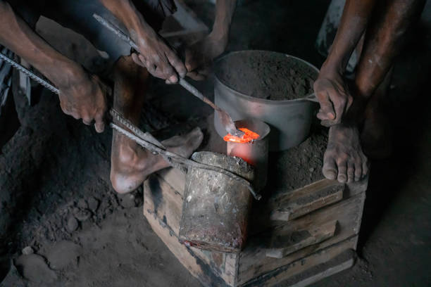 Two men, just hands, working with burning material, waist material, they use for making new aluminum cooking pots. Andasibe, east from the Antananarivo.
