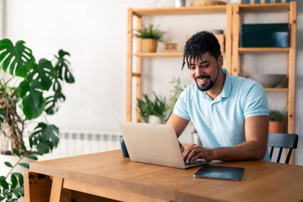 istock Content young businessman typing on a laptop, writing an e-mail, working and smiling. Home office concept 2154356231