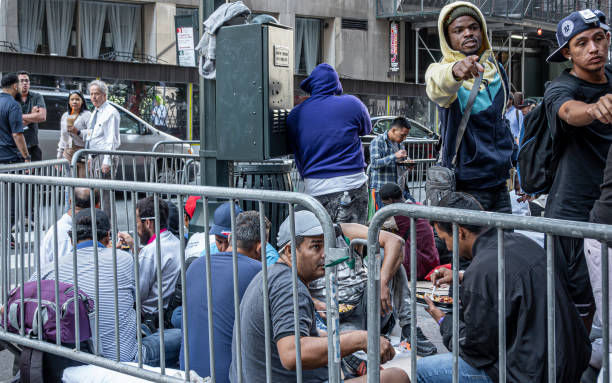 New York, NY, USA - August 2, 2023: Illegal immigrants corralled on the corner of Vanderbilt and E 45th in front of Roosevelt Hotel. they have just been fed by government