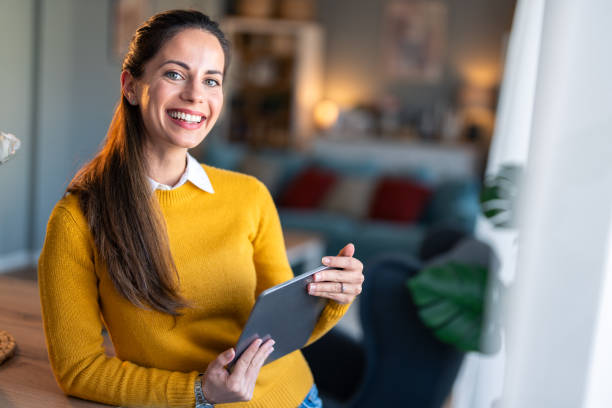 istock Beautiful smiling woman looking at camera and holding digital tablet, posing for a portrait photo 2154358921