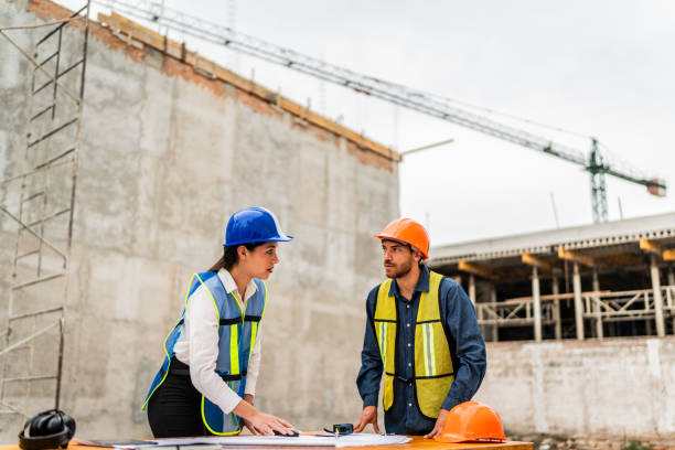 istock Coworkers talking and looking the blueprint on construction site 2154368284