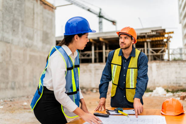 istock Coworkers talking and looking the blueprint on construction site 2154368297
