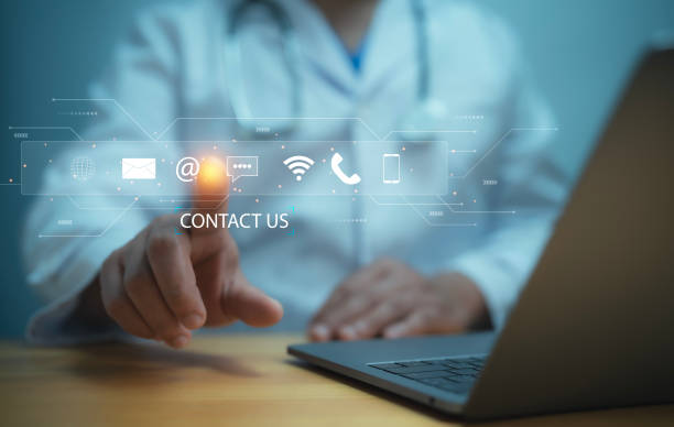 istock Medical worker using a laptop and touching on virtual screen contact icons email, address, live chat, internet wifi. Contact us or Customer support hotline people connect 2154371935