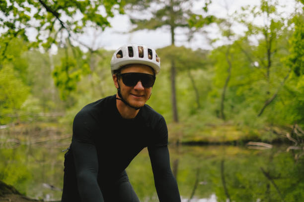 istock Road bicyclist rides by lake in forest 2154371961