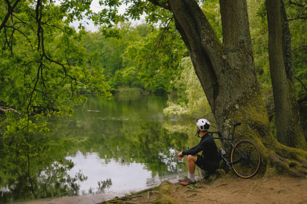 istock Road bicyclist relaxes by lake in forest 2154371993