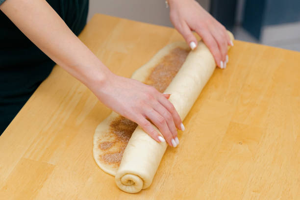 istock One Caucasian young girl rolls cinnamon dough into a roll on the table. 2154372018
