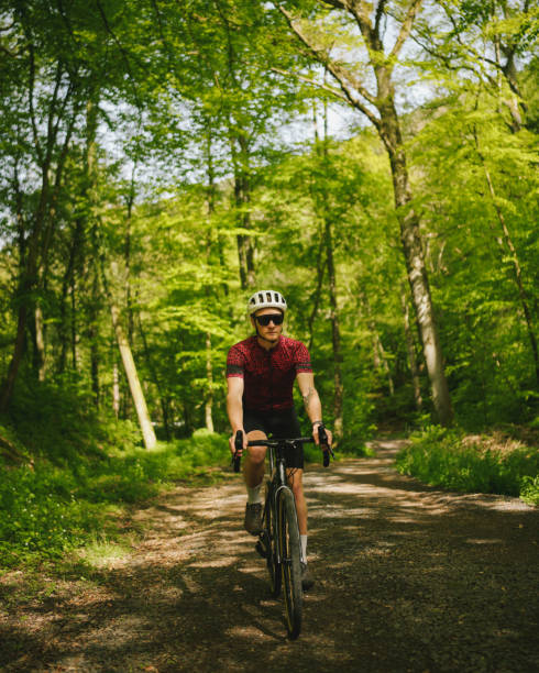 istock Road bicyclist rides through lush forest 2154372100