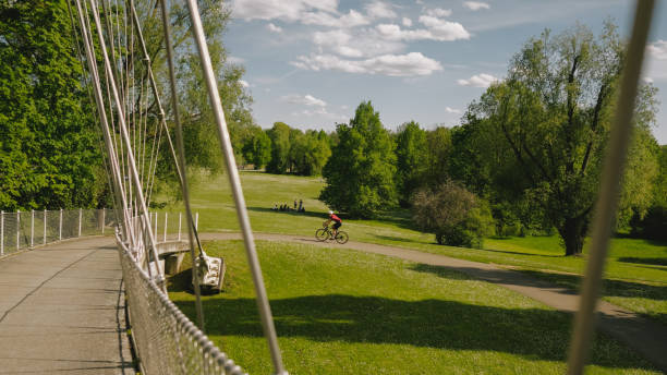 Road bicyclist rides across suspension bridge in lush forest