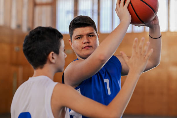 istock A junior basketball player passing a ball over his rival on training. 2154373062