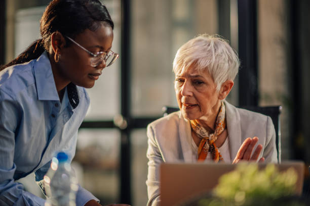 istock Old female manager discussing project with interracial colleague at office 2154373157
