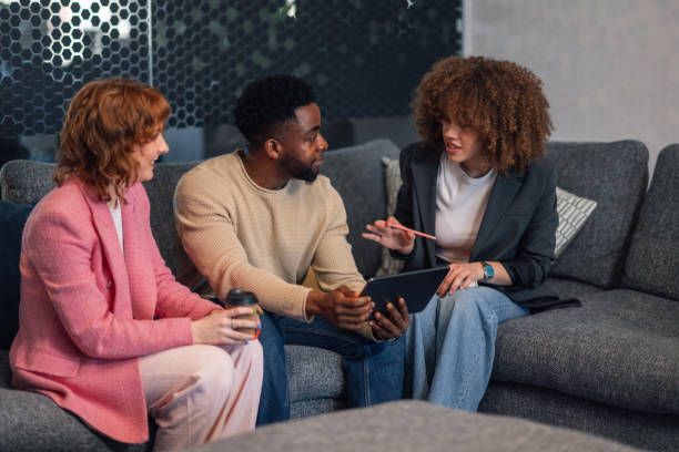istock Interracial staff on sofa with tablet brainstorming in office lobby. 2154373183