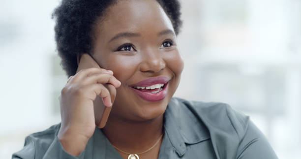 istock One happy young black business woman talking on cellphone while working in office. Face of confident smiling african american entrepreneur communicating on phone call while networking and planning 2154381263