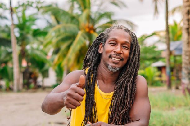 Close-up portrait of an African American man with his thumb up. Middle aged man with dreadlocked hair smiling at the camera.