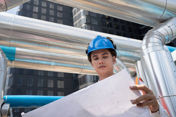 istock Portrait Asia male engineer in protective workwear is performing a conducts system check with use paper work at rooftop building 2154395984