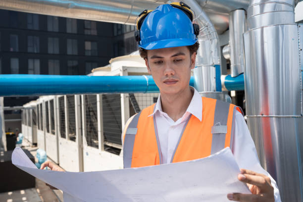 istock Portrait Asia male engineer in protective workwear is performing a conducts system check with use paper work at rooftop building 2154395991