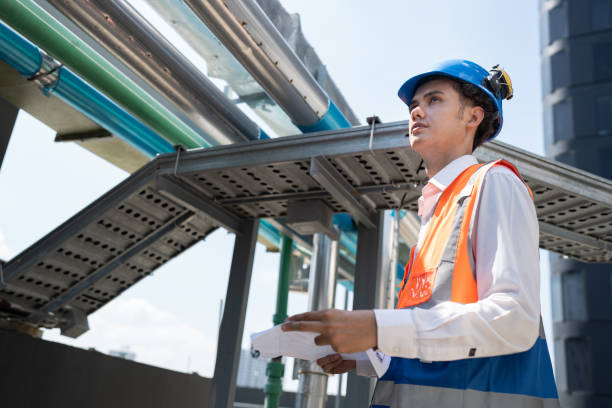 istock Portrait Asia male engineer in protective workwear is performing a conducts system check with use paper work at rooftop building 2154395995