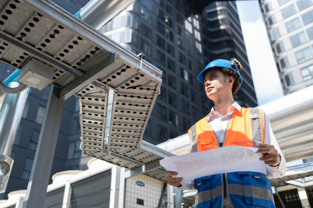 istock Portrait Asia male engineer in protective workwear is performing a conducts system check with use paper work at rooftop building 2154396012