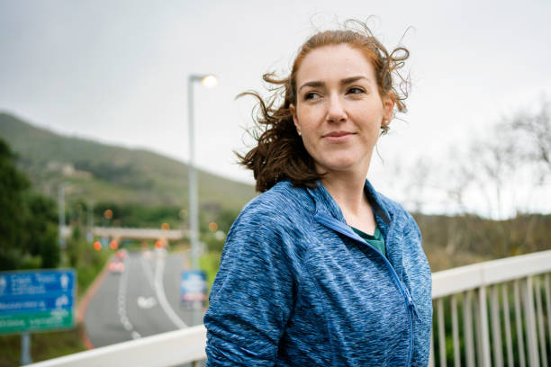 istock Smiling woman in sportswear while standing on a bridge during a run 2154398065