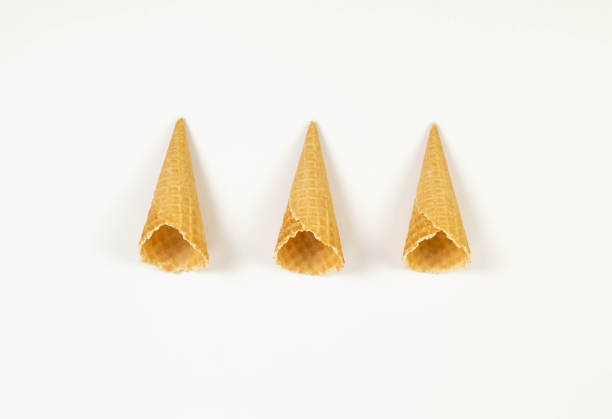 Top view of three ice cream waffle cones on white background. Summer wallpaper, flat lay, copy space.