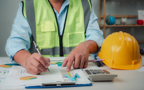 istock A foreman sits at a desk in an office, Calculating costs, Planning construction, Calculating structures, Planning and calculating project construction costs, Project presentation plan. 2154403120