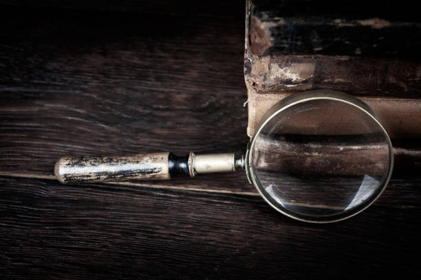 Old vintage magnifying glass with books on wooden table