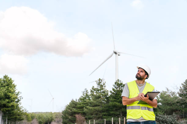 istock Technician Looking at Wind Turbines with Clipboard in Hand 2154406672