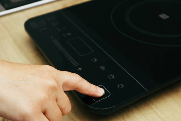 istock Woman hand turn on induction stove. Finger touching sensor button on induction or electrical hob. Modern kitchen appliance. 2154411727