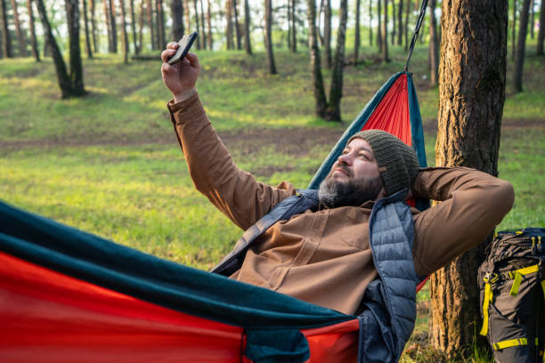istock A positive man laying in hammock in the forest and uses smartphone for selfie while 2154413541
