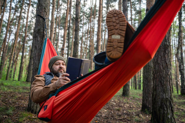 istock Carefree man laying in hammock and reading a book 2154413565