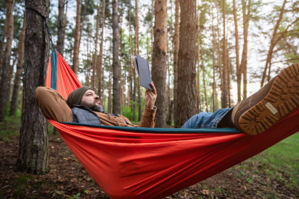 istock A man reading a book in hammock in the woods 2154413603