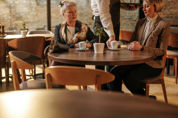 istock Waiter serving businesswomen in a cafe. 2154414964
