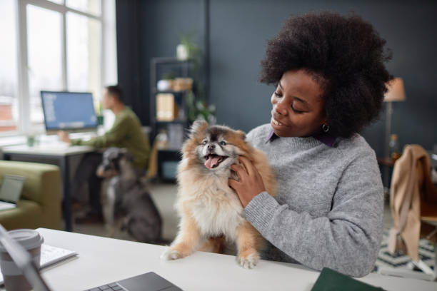 Smiling Black Woman Cuddling with Dog in Pet Friendly Office