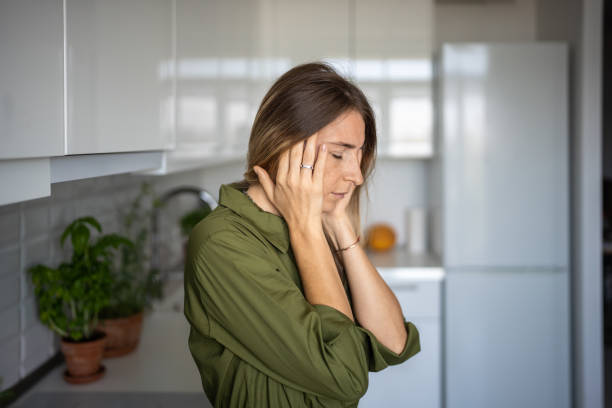 istock Tired woman feeling headache rubbing temples standing on kitchen with closed eyes. 2154417459