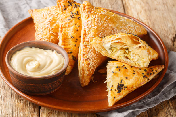 istock Triangular sesame puff pastry filled with chicken, cheese and herbs close-up in a plate. Horizontal 2154419659
