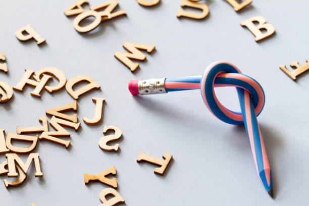 Pencil with knot and scattered letters, dyslexia concept